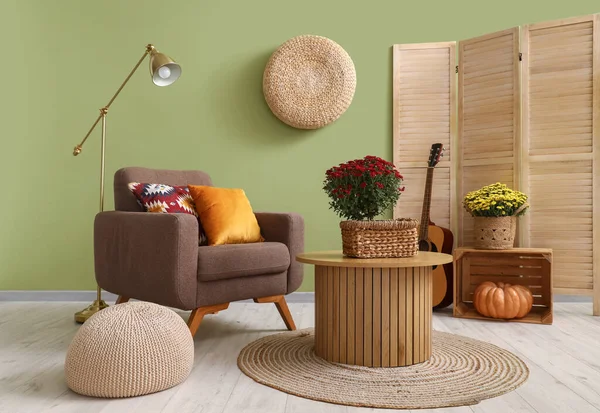 Interior of stylish living room with brown armchair, wooden coffee table and autumn flowers