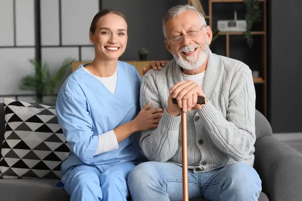Senior man with stick and nurse at home