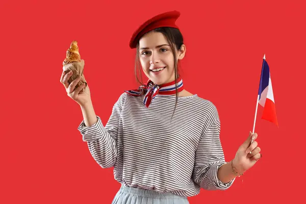 Young woman with flag of France and croissant on red background