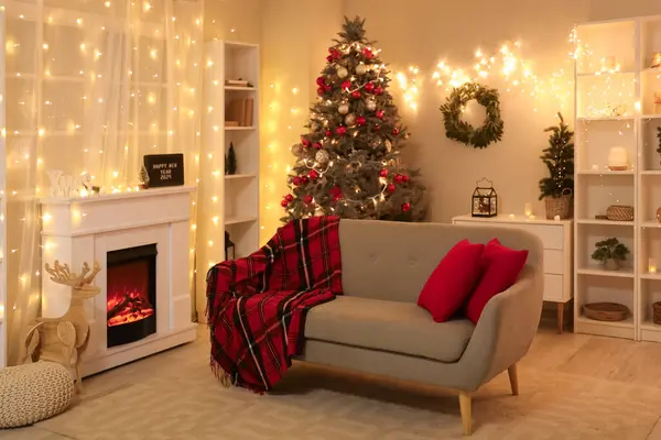 Interior of living room with Christmas trees, sofa and glowing lights in evening
