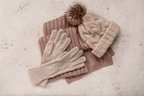 Knitted gloves with warm hat and scarf on white grunge background
