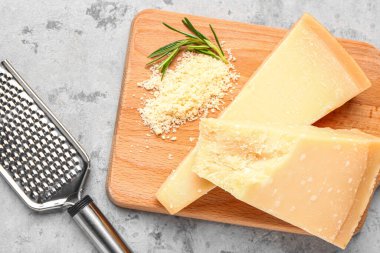 Arkaplanda lezzetli parmesan peyniri parçaları olan ahşap tahta pano, yakın plan.
