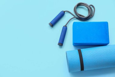 Yoga minderi, ip atlama ve mavi arka planda köpük egzersiz bloğu