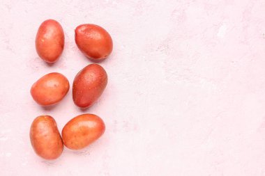 Pembe arka planda taze çiğ patates.