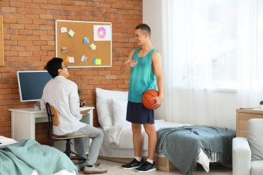 Genç bir çocuk yurt odasında basketbol oynamasını öneriyor.