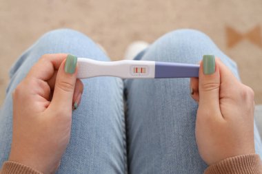 Evde pozitif gebelik testi olan genç lezbiyen kadın, yakın plan.
