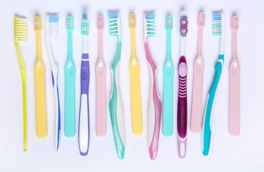 Beyaz arkaplanda renkli plastik diş fırçaları.