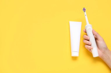 Turkuaz arka planda diş fırçası ve diş macunu olan bir kadın eli..