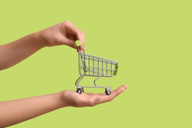 Arka planda yeşil alışveriş arabası olan kadın elleri.