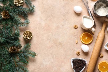 Noel pastası hazırlamak için farklı malzemelerden yapılmış çerçeve ve bej arka planda köknar dalları