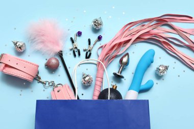 Farklı seks oyuncakları ve mavi arka planda Noel dekoru olan bir alışveriş çantası.