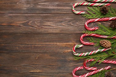 Noel şeker kamışları kozalaklı dallar ve ahşap arka planda çam kozalakları