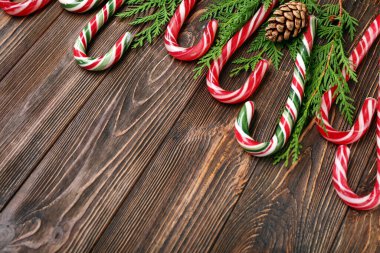 Noel şeker kamışları kozalaklı dallar ve ahşap arka planda çam kozalakları