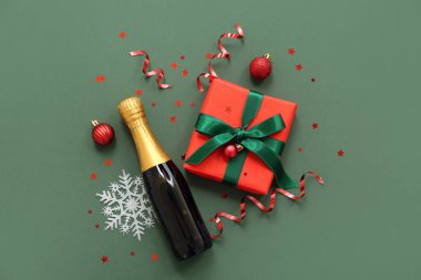 Hediye kutulu şampanya şişesi ve yeşil arka planda Noel dekoru.