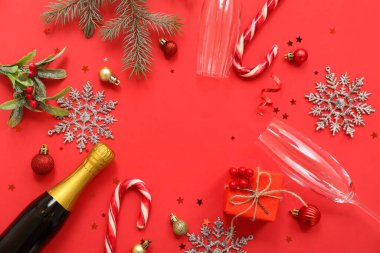 Şampanya şişesi ve kırmızı arka planda Noel süsü olan gözlüklerden yapılmış çerçeve.