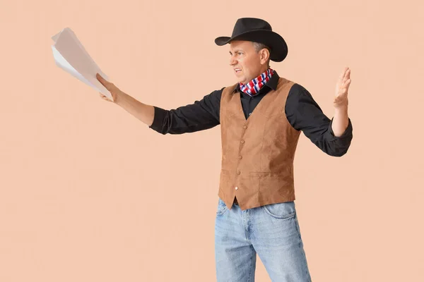 Mature actor dressed as cowboy reading film script on beige background