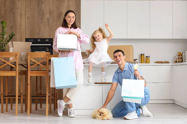 Happy family with laptop and shopping bags in kitchen