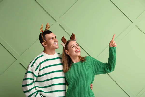 Beautiful Young Couple Reindeer Horns Pointing Something Green Background — Stock Photo, Image