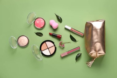 Makyaj ürünleri ve yeşil arka planda güzel çiçeklerle süslü bir makyaj çantası.