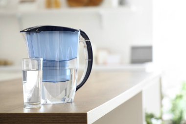 Su filtresi sürahisi ve mutfak masasında cam.
