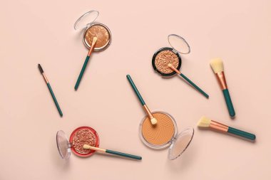 Pembe arka planda makyaj fırçaları ve farklı dekoratif kozmetikler