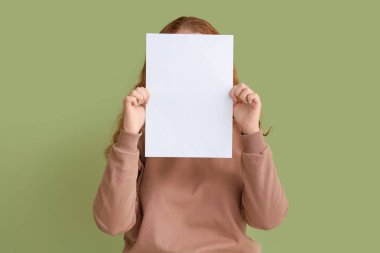 Yeşil arka planda boş kağıt sayfası olan genç bir kadın.