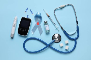 Mavi arka planda glukometre, tükenmez kalem ve insülin ile farkındalık kurdelesi. Diyabet kavramı