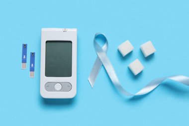 Mavi arka planda glukometre ve şeker ile farkındalık kurdelesi. Diyabet kavramı