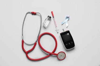 Işık arka planında insülin, glukometre ve steteskoplu farkındalık şeridi. Diyabet kavramı