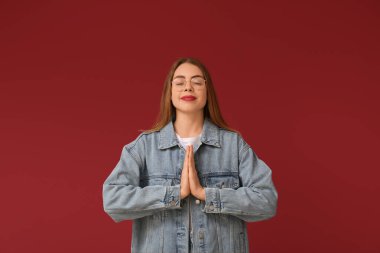 Güzel genç bir kadın kırmızı arka planda meditasyon yapıyor. Zen kavramı