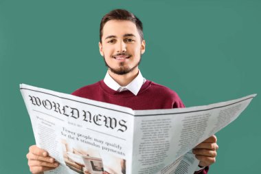 Genç adam yeşil arka planda gazete okuyor.