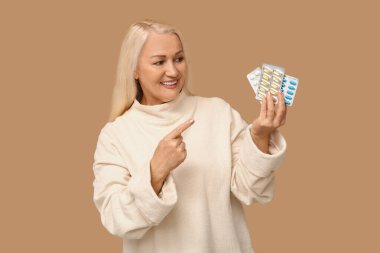 Kahverengi arka planda haplara işaret eden olgun bir kadın.