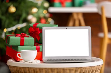 Ofisteki masada bardaklı ve noel hediyeli boş dizüstü bilgisayar, yakın plan.