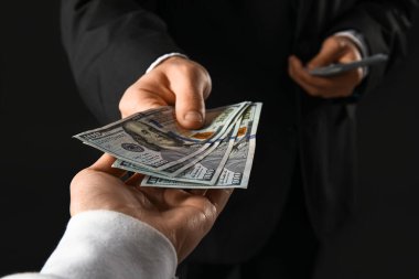 Genç işadamı karanlık arka planda rüşvet veriyor, yakın plan.
