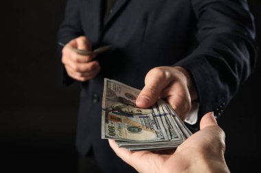 Genç işadamı karanlık arka planda rüşvet veriyor, yakın plan.