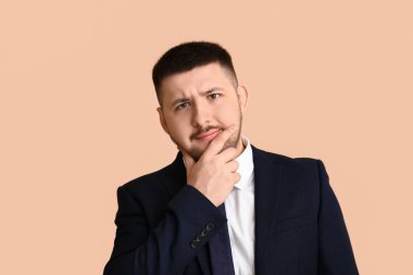 Bej arka planda genç ve düşünceli bir iş adamı. İş fikri kavramı