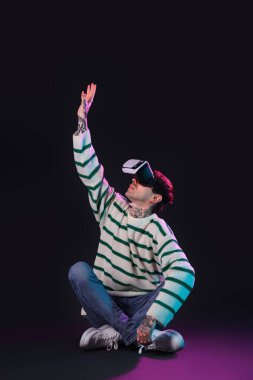 Siyah arka planda VR gözlüğü kullanan genç adam.