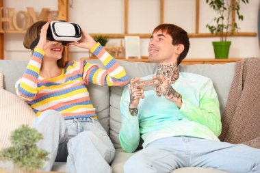 Cep telefonu ve kız arkadaşı evde VR gözlüğü takan genç bir adam.