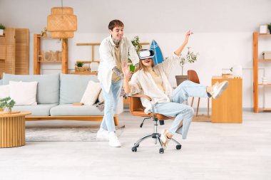 Genç adam ve kız arkadaşı evde VR gözlüğü kullanıyorlar.