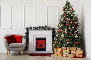 Oturma odasının içinde şömine, koltuk ve Noel ağacı var.
