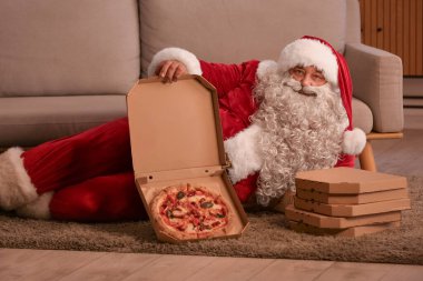 Noel arifesinde lezzetli pizzalı Noel Baba evde yatıyor.