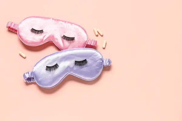 Composition with sleep masks, false eyelashes and pills on pink background