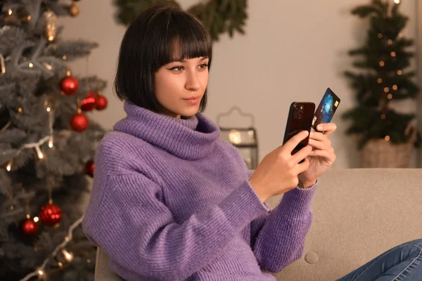 Young woman with credit card and mobile phone shopping online for Christmas at home