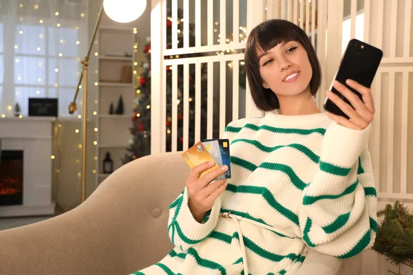 年轻女子带着手机和信用卡在网上购物 在家里过圣诞 — 图库照片
