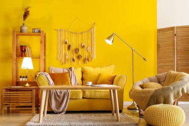 Şık bir oturma odası, rahat sarı koltuğu ve parlak lambaları var.