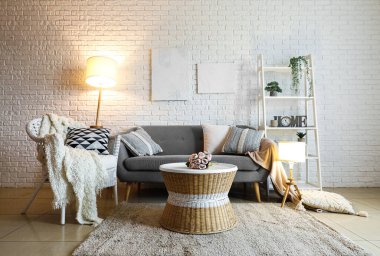 Oturma odasının içi rahat gri kanepe ve parlak lambalarla dolu.