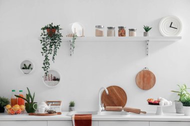 Beyaz tezgah ve rafta farklı mutfak aletleri var.