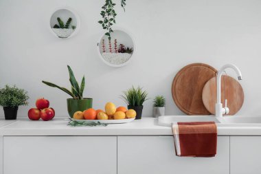 Lavabosu, çiçekleri ve taze meyveleri olan beyaz mutfak tezgahı.