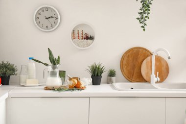 Lavabosu, kruvasanı ve çiçekleri olan mutfak tezgahı.