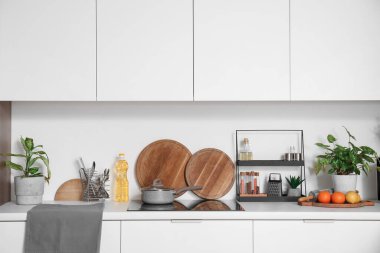 Modern mutfağın beyaz tezgahında tencere ve çatal bıçak ile elektrikli soba.